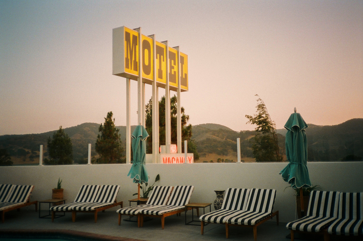 Enseigne d'un motel californien jaune avec transats rayés en premier plan