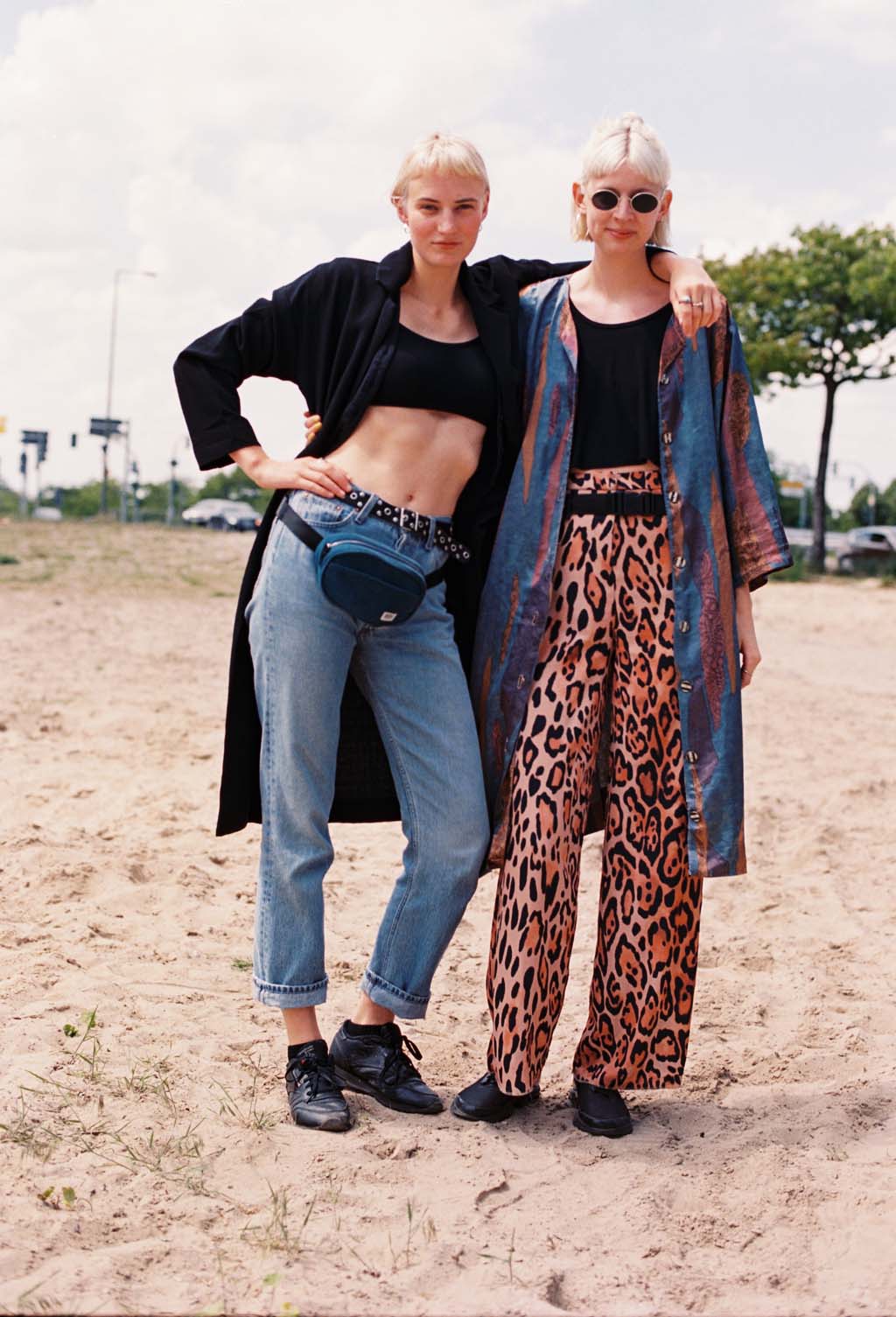 Deux femmes en jean et pantalon panthère se tenant par l'épaule dans une fête de jour à berlin