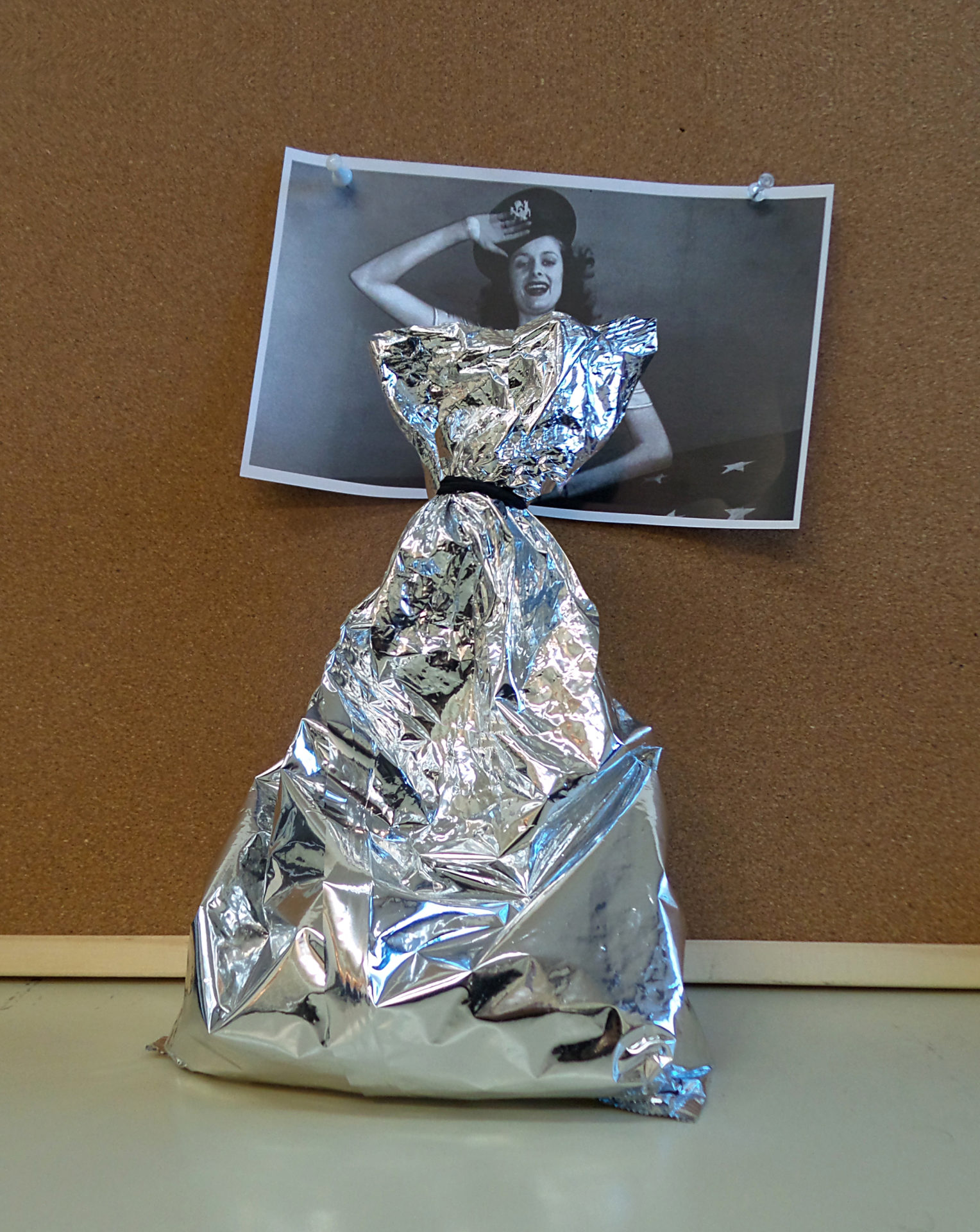 Sachet en aluminium plié formant une robe sur une photo de femme en noir et blanc