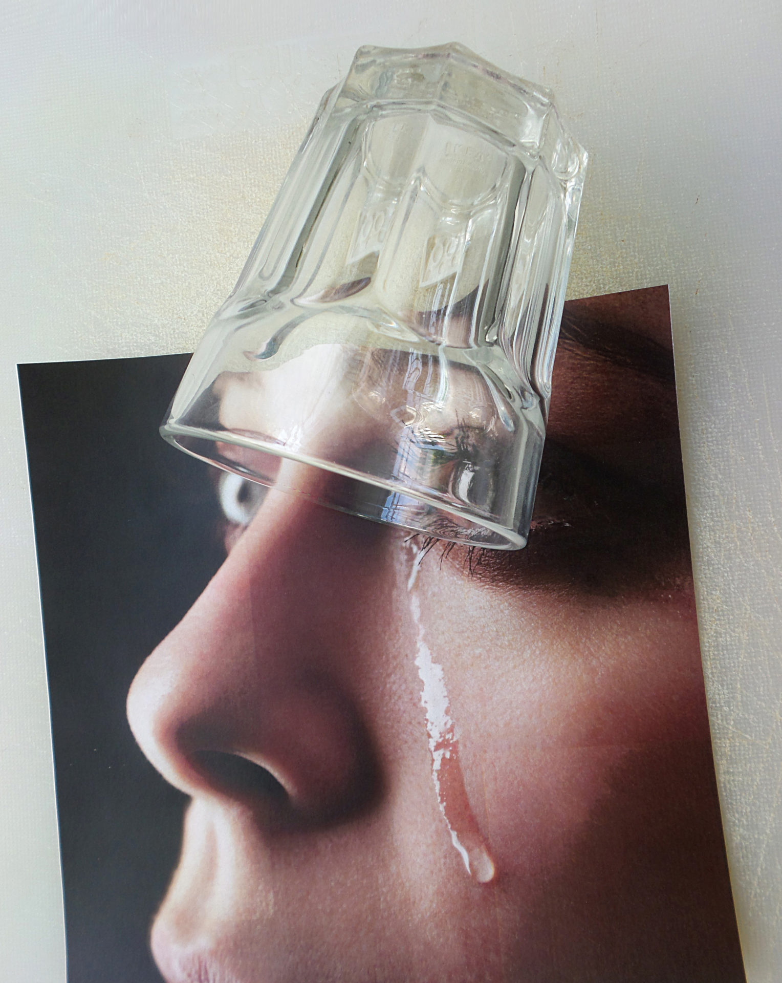 Verre d'eau renversé sur une photo de femme formant une larme sur sa joue