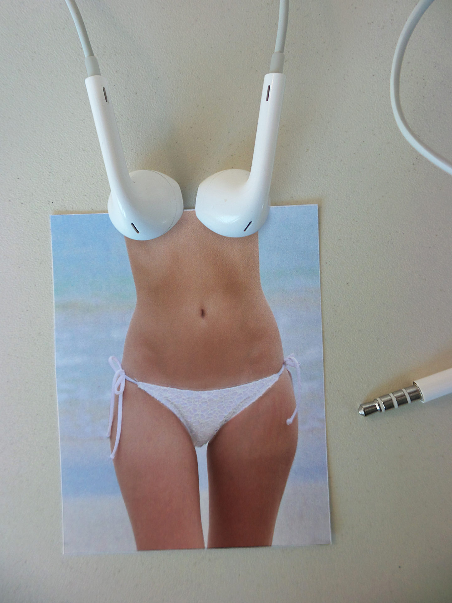 Ecouteurs formant un soutien-gorge posé sur une photo de femme en bikini blanc