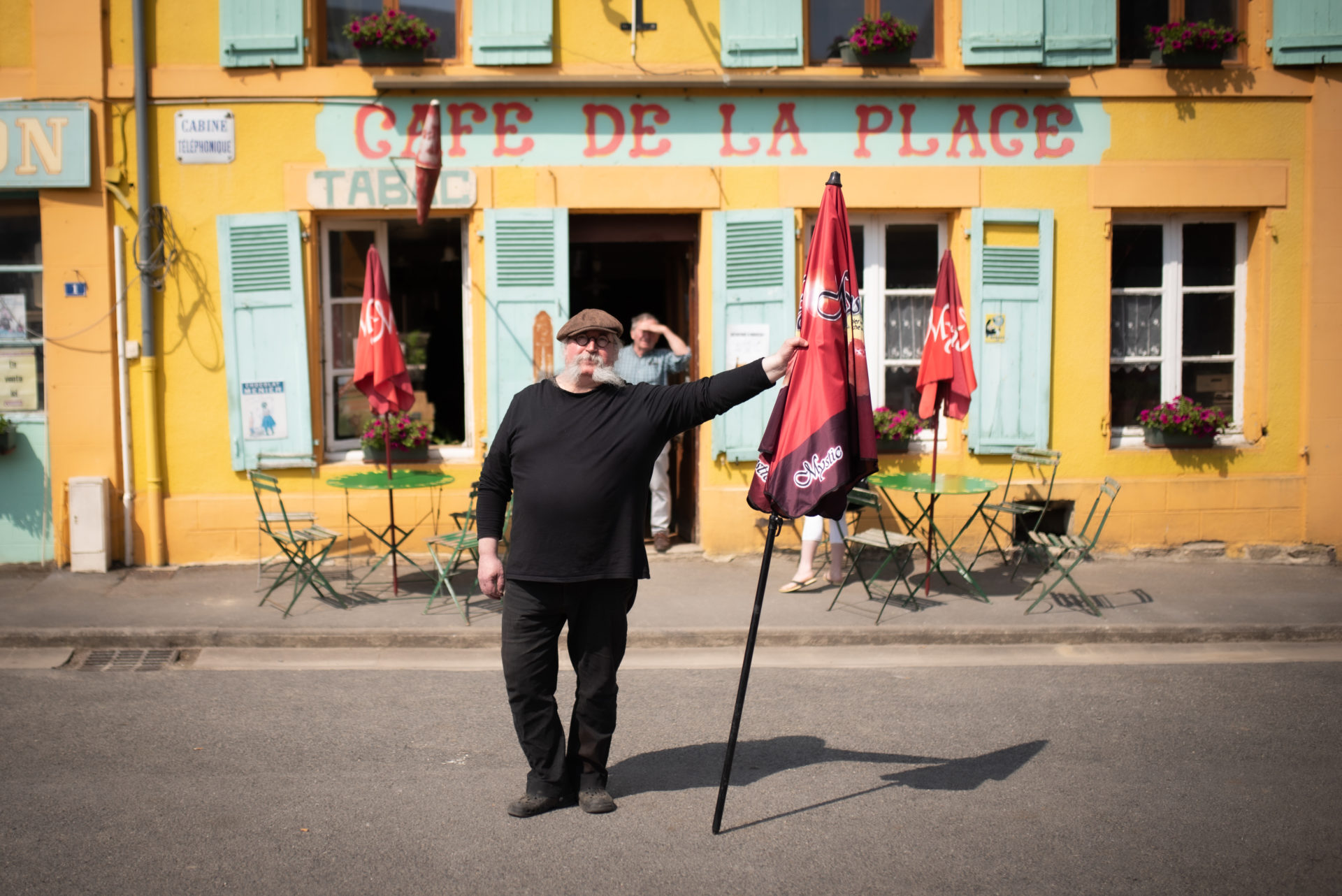 Fabrice Quinart, posant avec un parasol, devant son Café de la Place (Brieulles-sur-Bar, France), le 9 juin 2021.