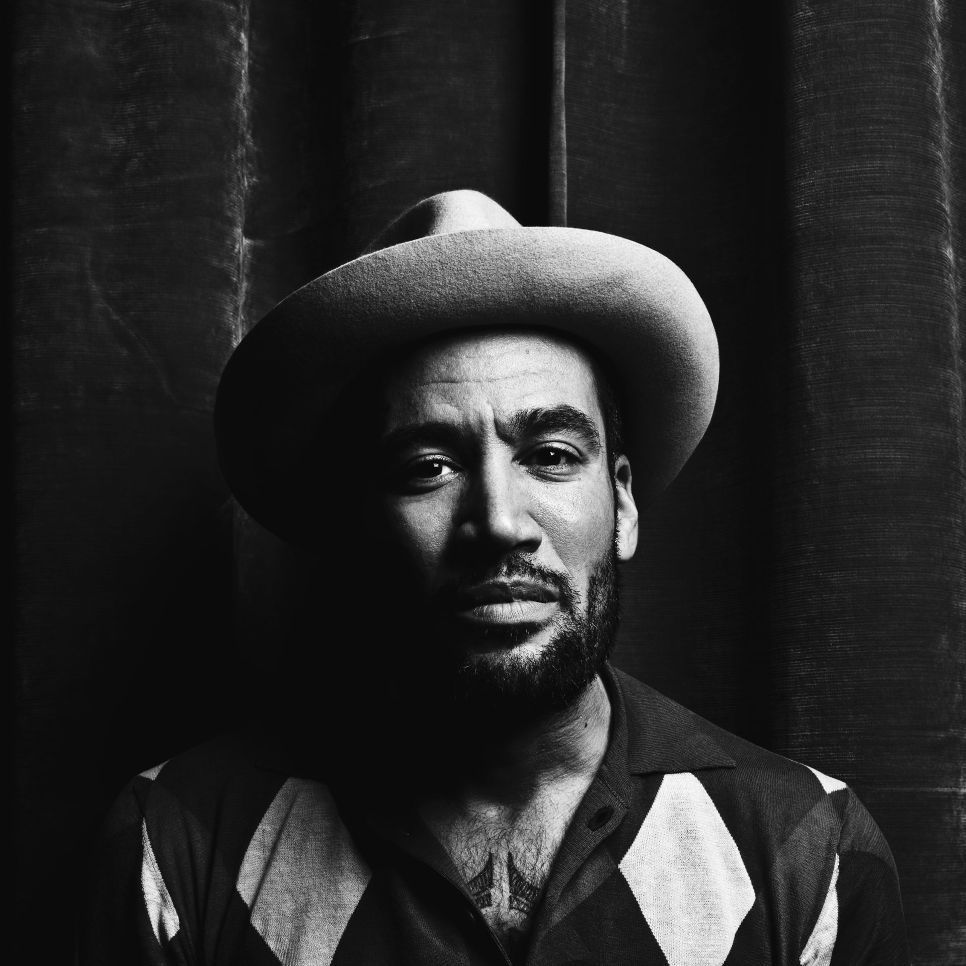 Portrait en noir et blanc d'un homme avec un pull jacquart et un chapeau
