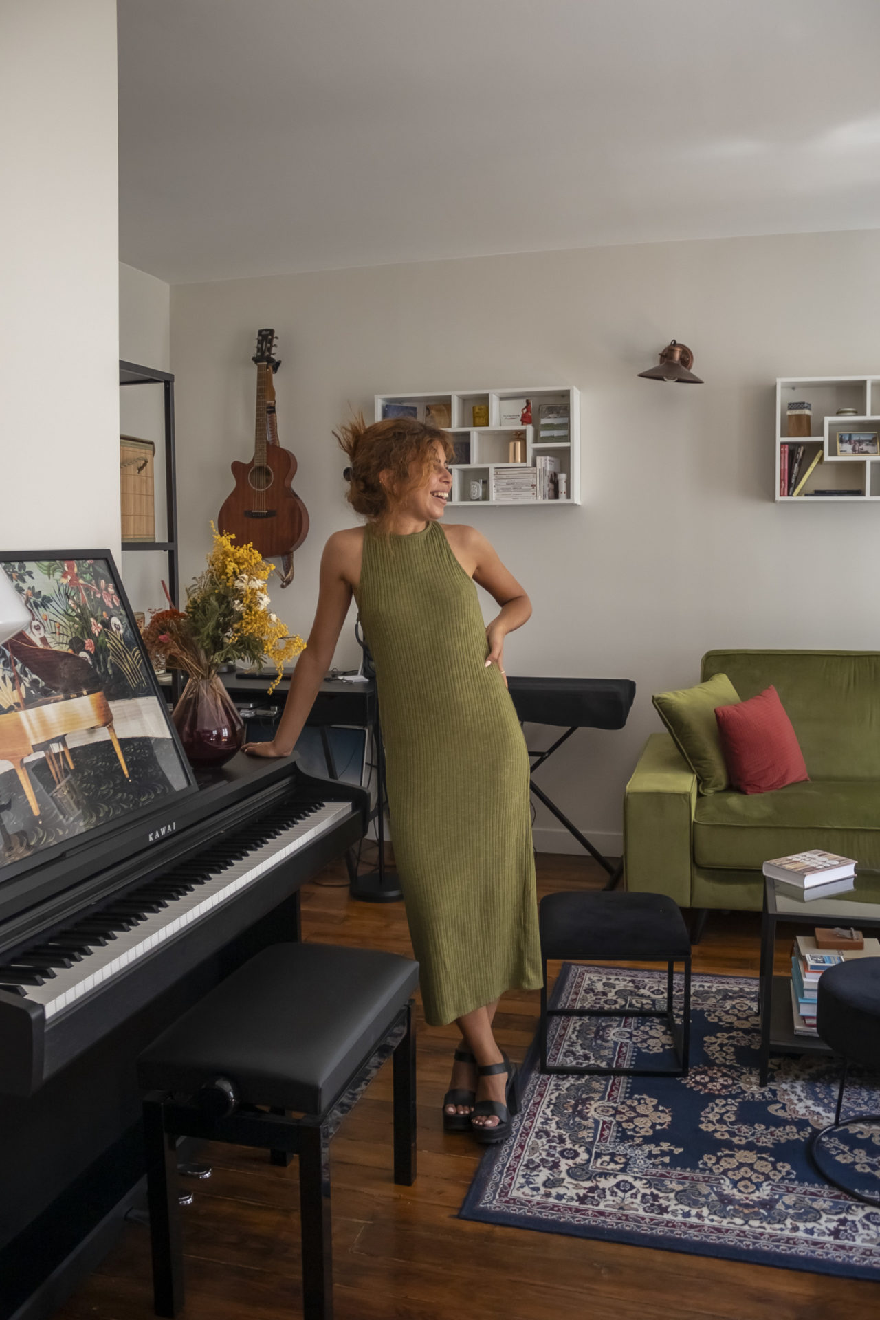 Laurie Darmon prenant la pose dans son salon avec une main posé sur son piano