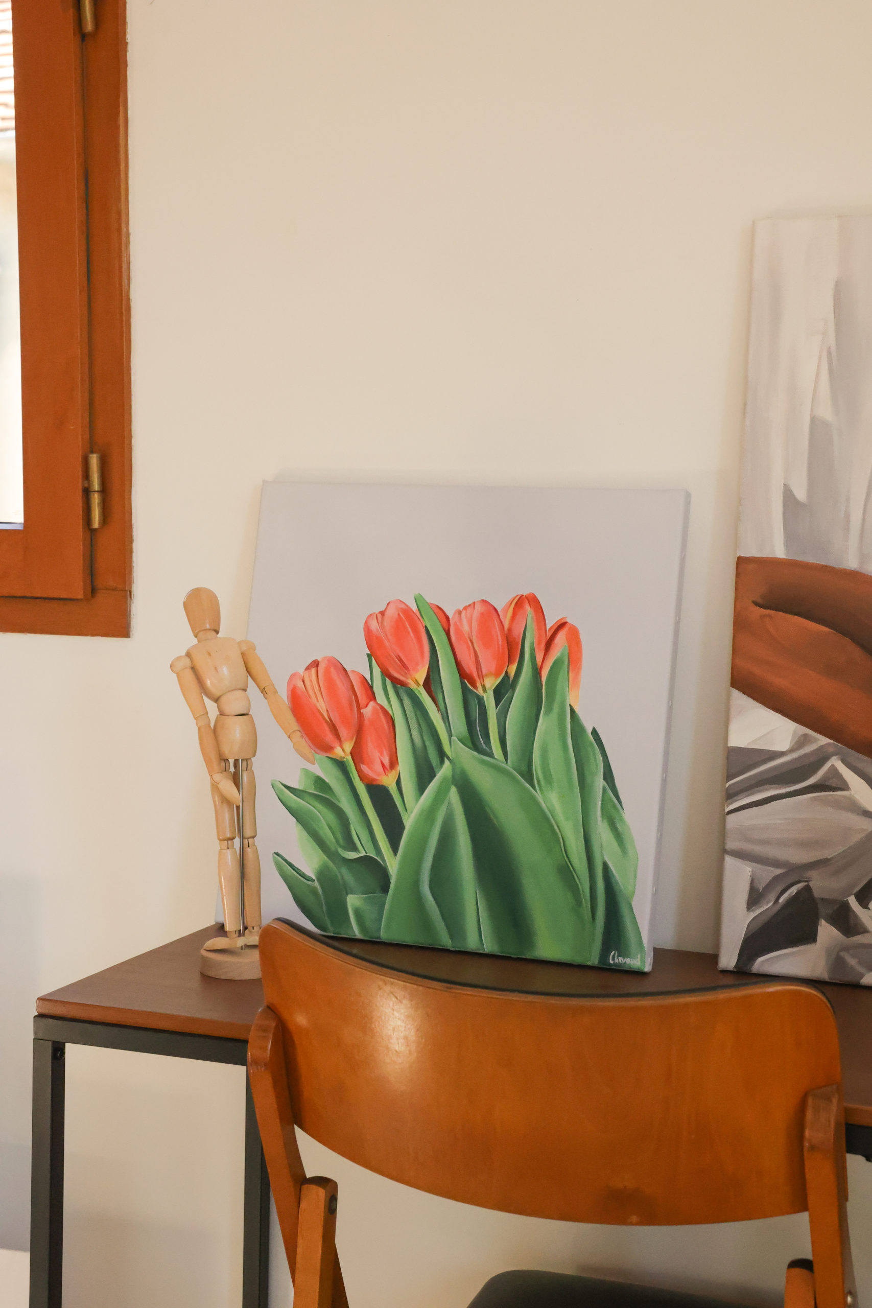 Peinture de tulipe rouge posée sur un bureau à côté d'un pantin de dessin.