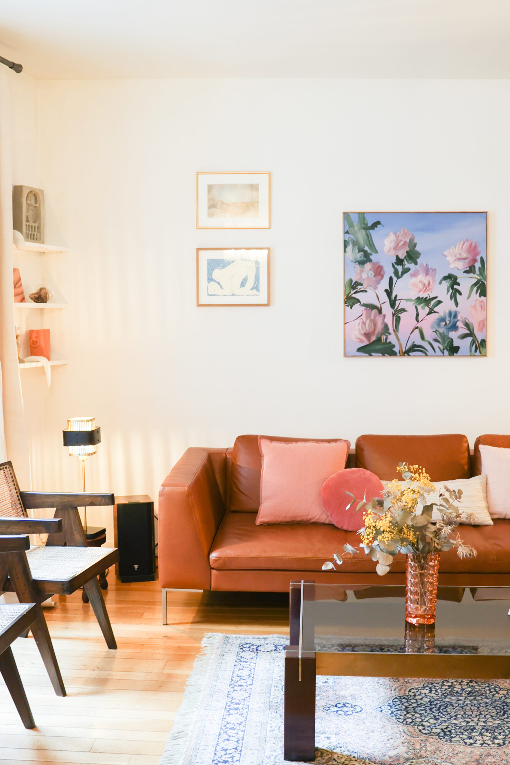Interieur composé d'un canapé en cuir marron, de chaises designs et d'oeuvres d'art accrochés aux. murs
