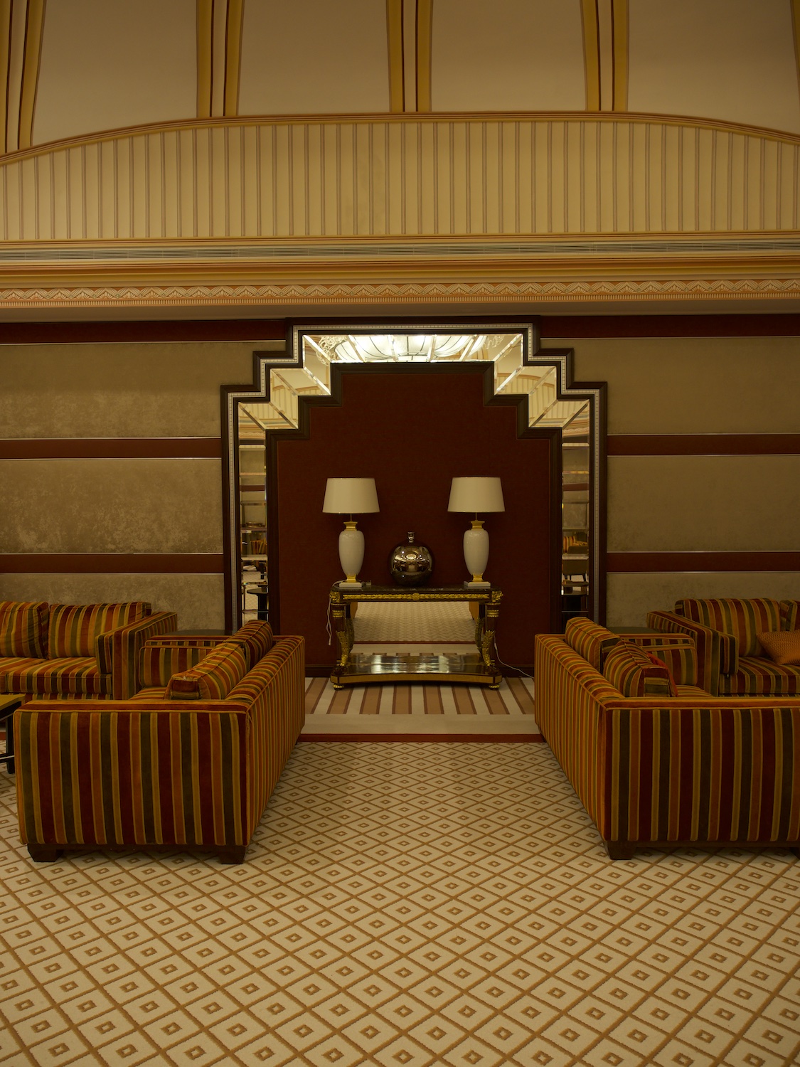 Photo de l'interieur du Carlton de Djeddah. 2 fauteuils rouge et doré devant un mur de dorure