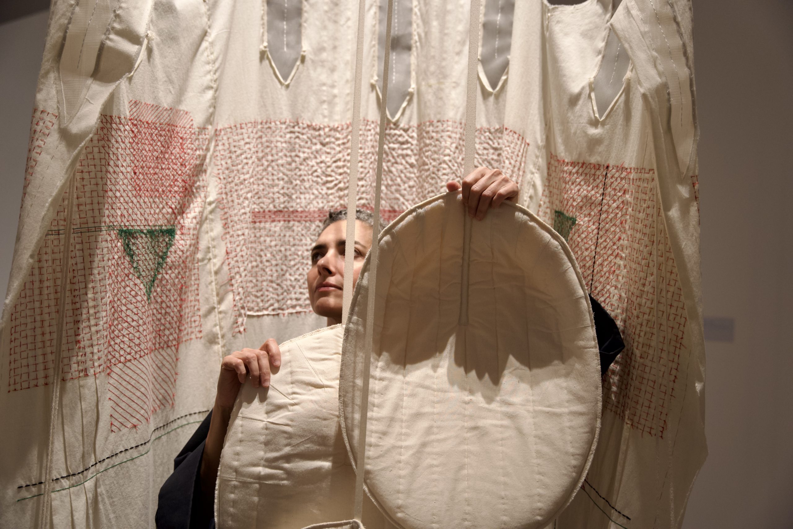 Portrait de l'artiste Filwa Nazer au milieu d'une de ses oeuvres en tissu clair