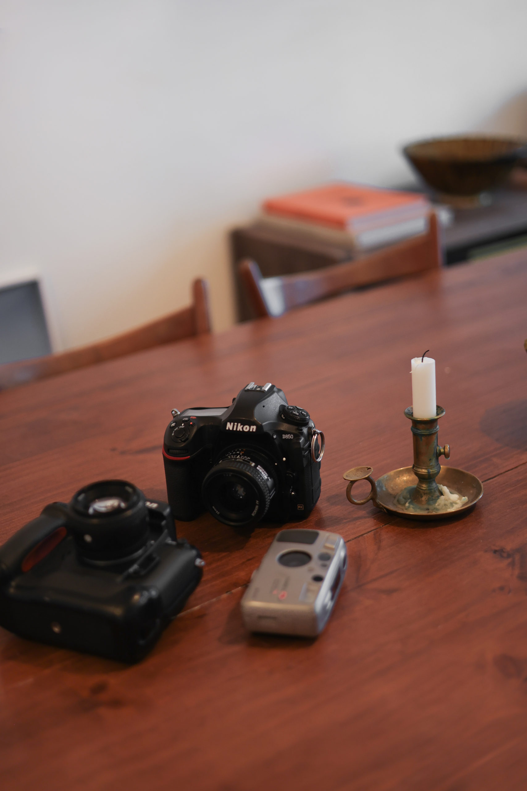 Les appareils photos de Bastien Lattanzio posés sur une table vintage en bois à côté d'un bougeoir