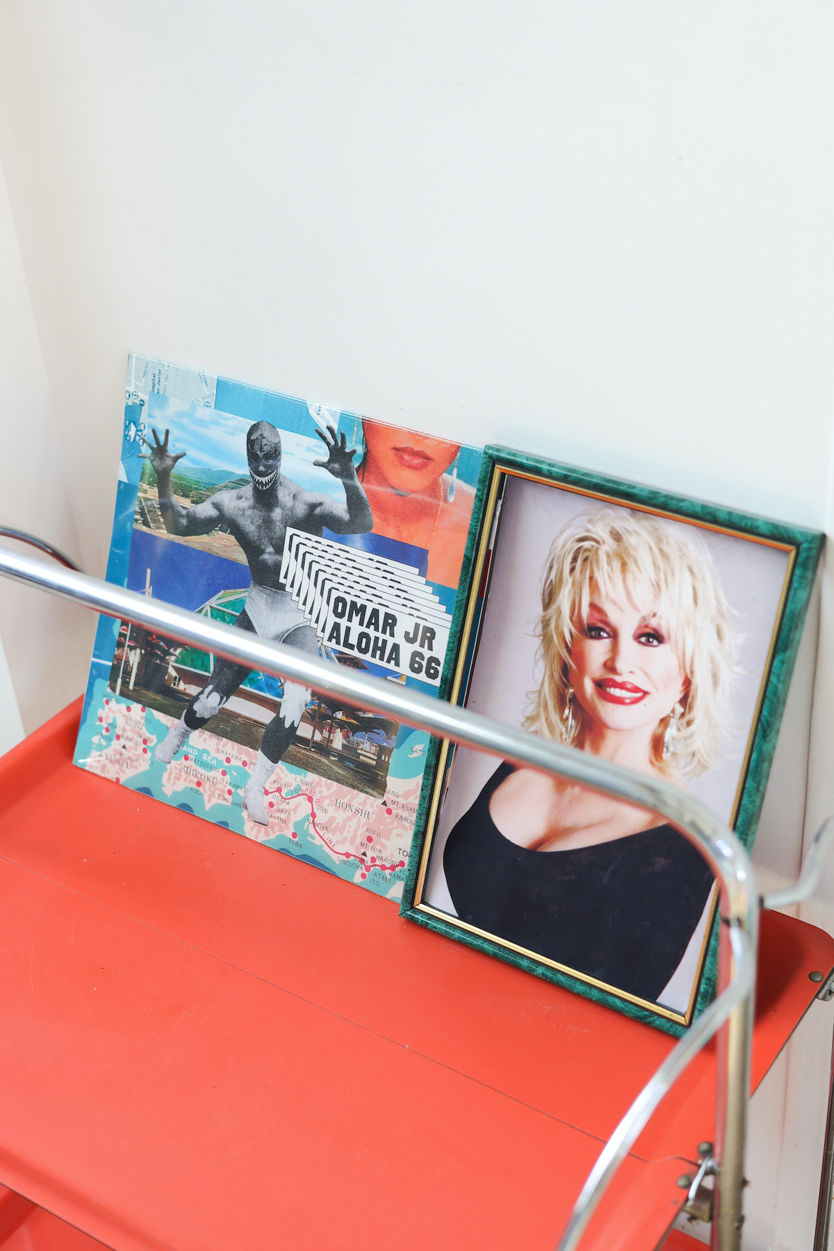 Cadre de Dolly Parton à côté d'un vinyle d'Omar JR "Aloha 66" sur une deserte vintage orange